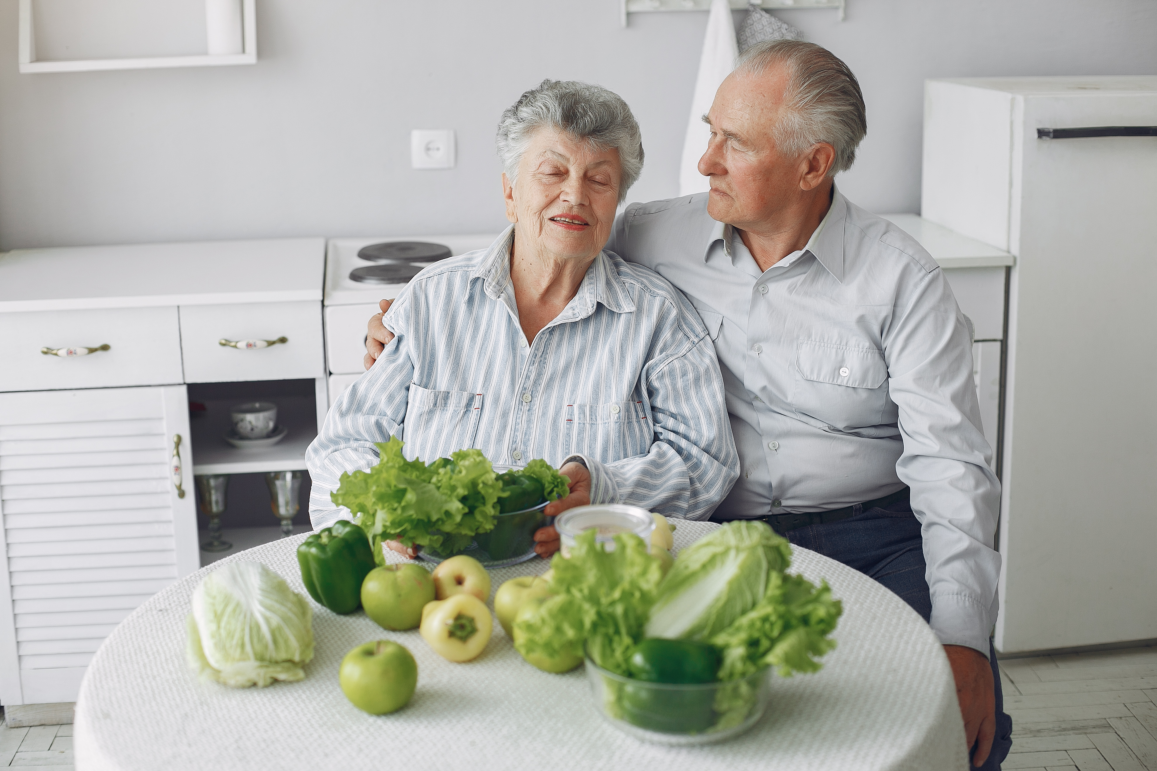 Beautiful old couple prepare food in a kitchen