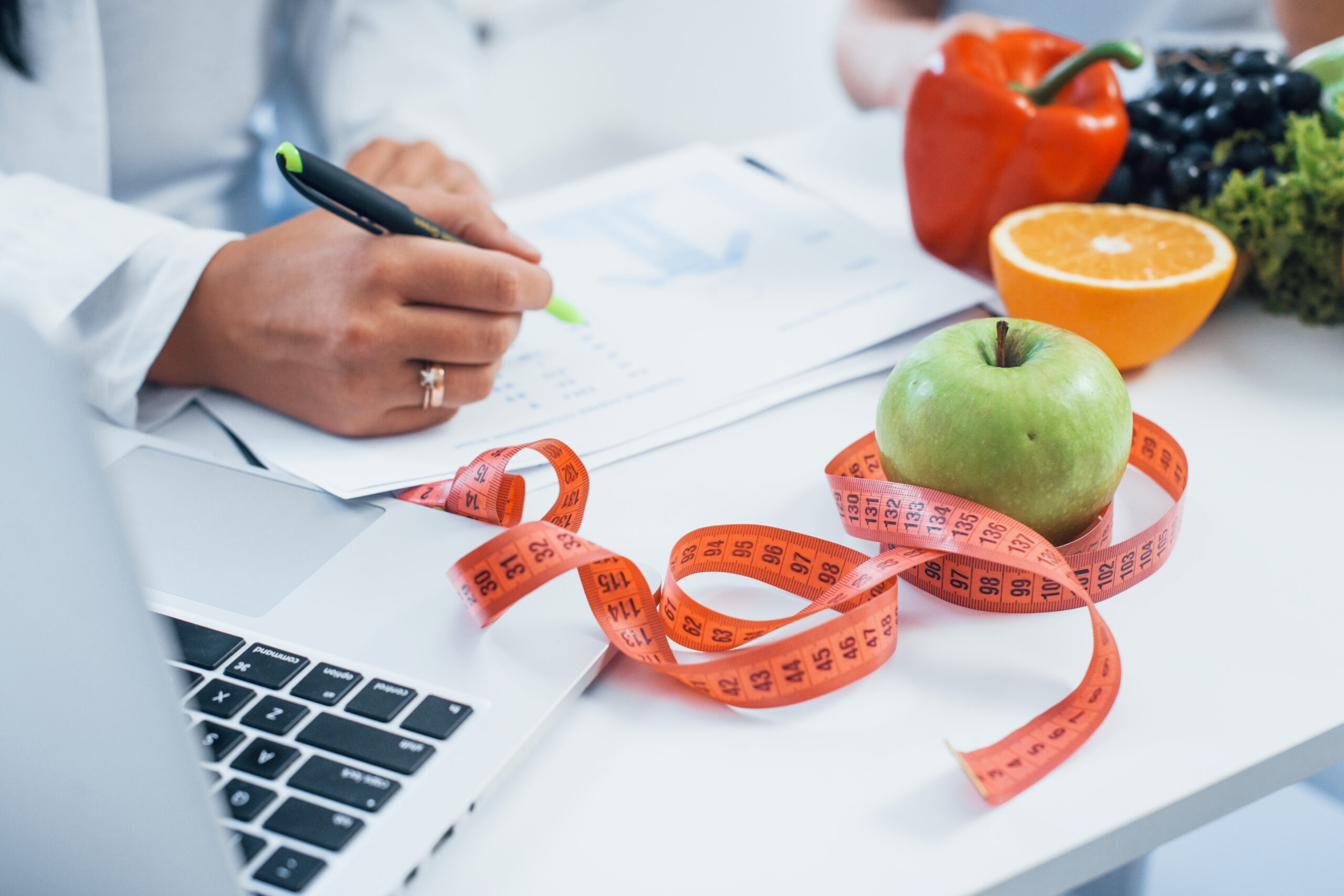 Female nutritionist in white coat sitting indoors in the office at workplace